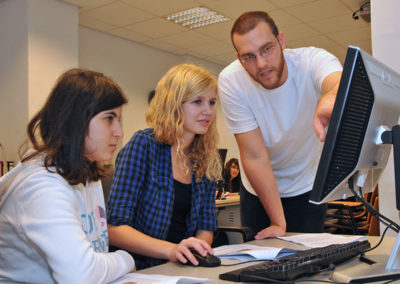 Schülerinnen am Computer bekommen etwas erklärt