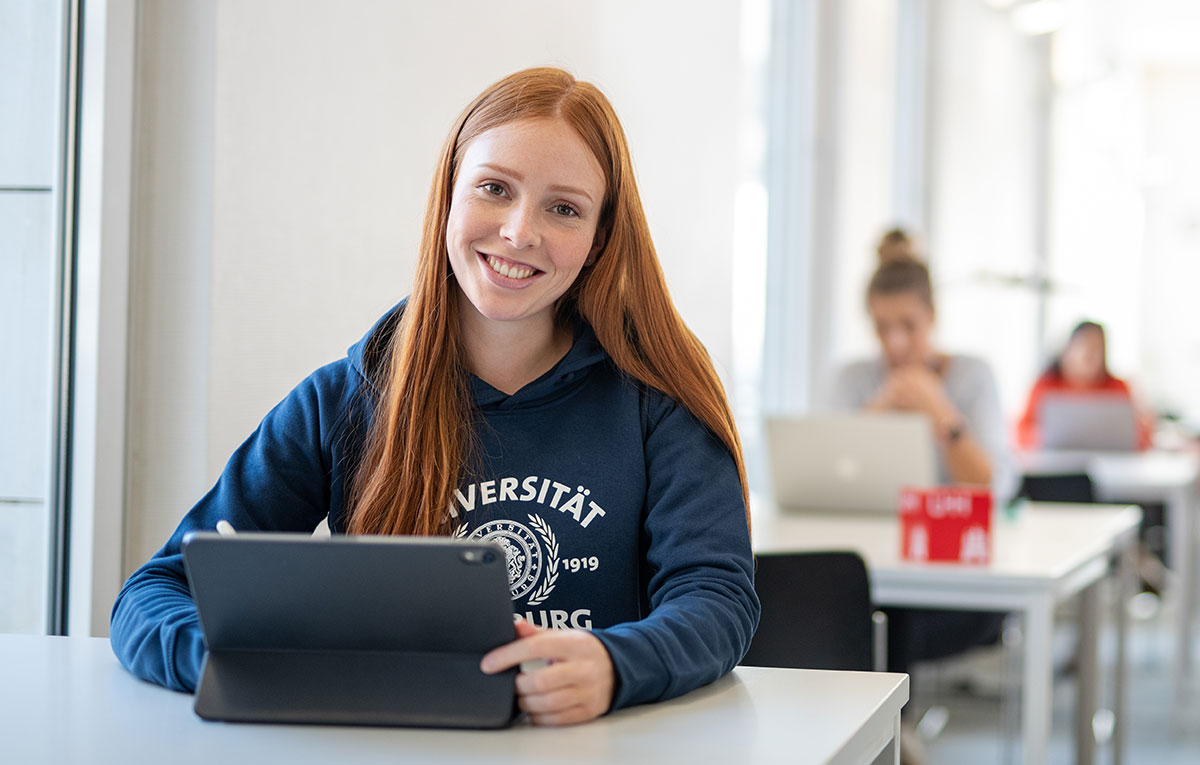 Studentin mit Tablet sitzt in einer Bibliothek 